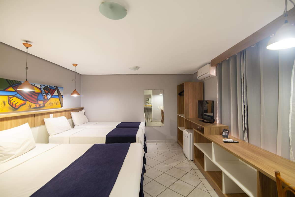 A hotel room with two beds, a TV, a desk, and a painting on the wall.
