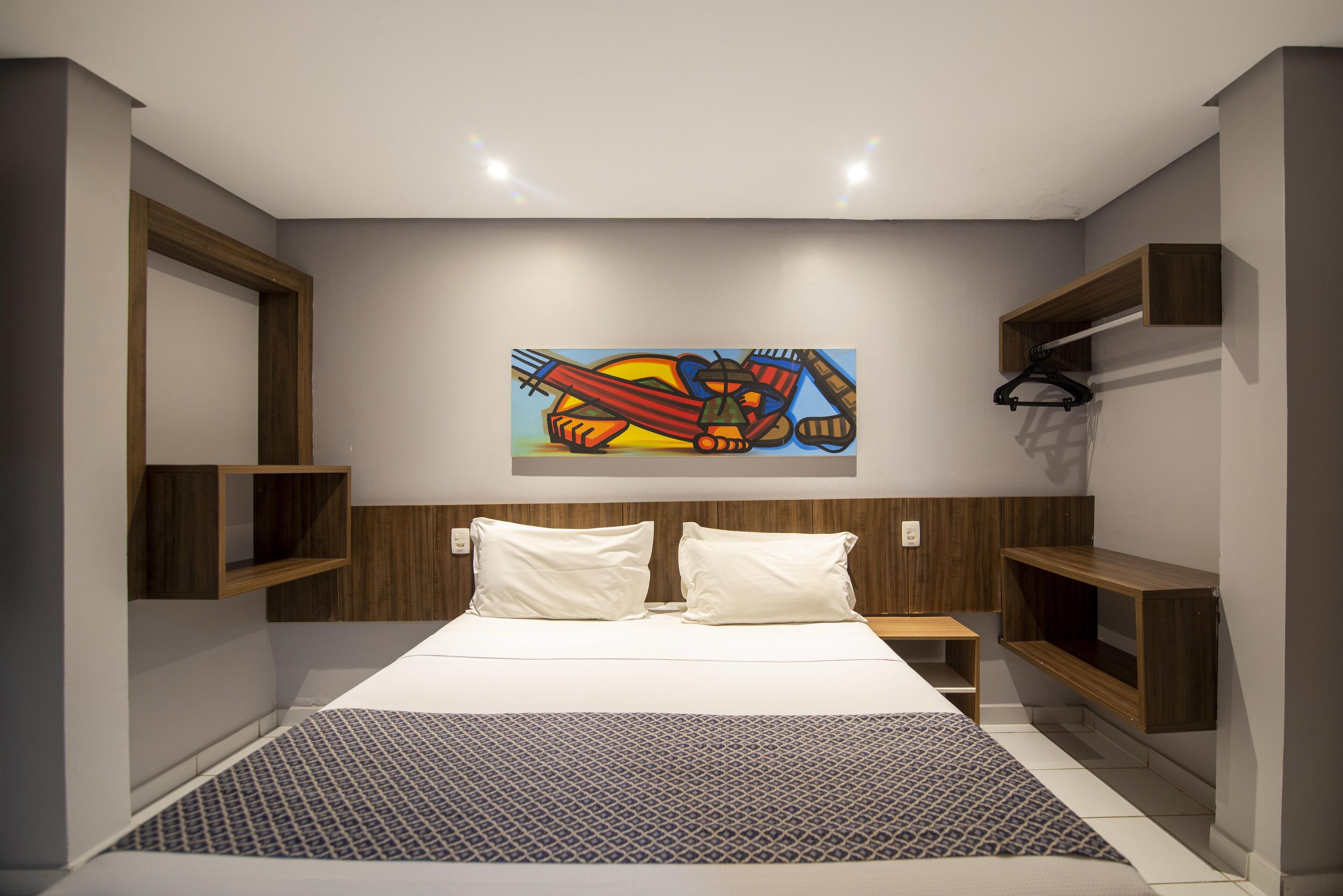 Un dormitorio moderno con una cama grande, cabecero de madera y estanterías empotradas.