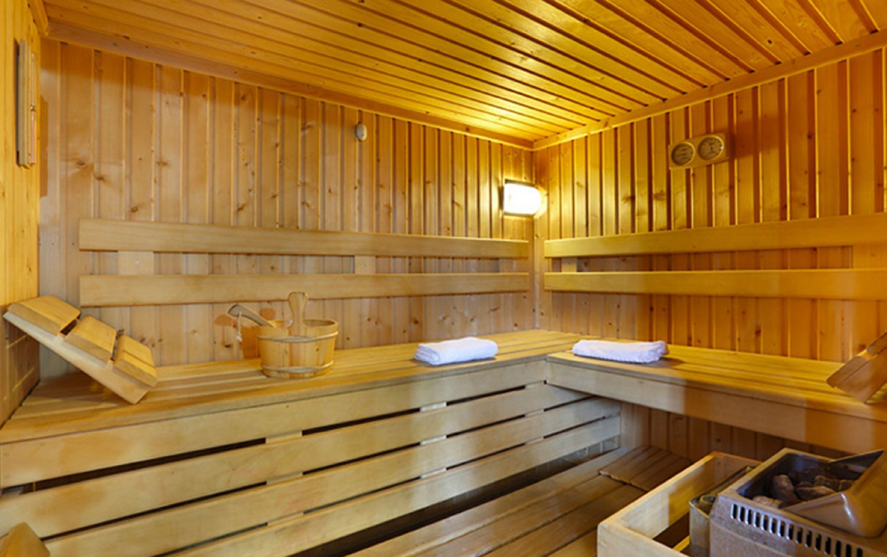 Una sauna de madera con bancos, una pequeña mesa con una toalla y un cubo.