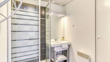 Une salle de bain moderne avec une douche à parois de verre, un lavabo avec un miroir et un porte-serviettes.
