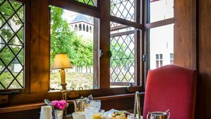 A breakfast table set with various food items and a view of a building through large windows.