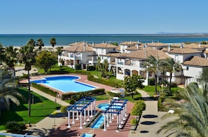 Un resort con una piscina grande, palmeras y vista al mar.