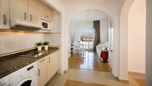 A modern kitchen with granite countertops, a built-in microwave, and a washing machine. - Leo Apartamentos San Bruno (Ayamonte)