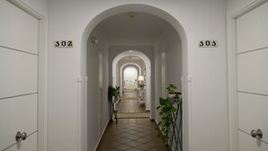 A hallway with arched ceilings, numbered doors, and a tiled floor. - Leo Apartamentos San Bruno (Ayamonte)