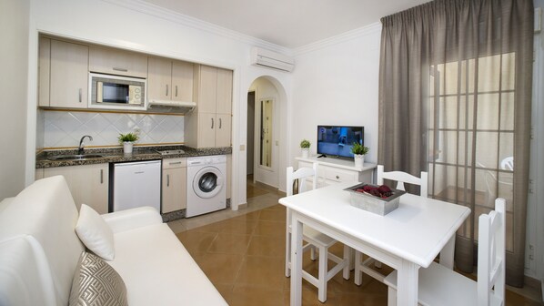 A compact living space with a kitchenette, a dining area, and a seating area. - Leo Apartamentos San Bruno (Ayamonte)