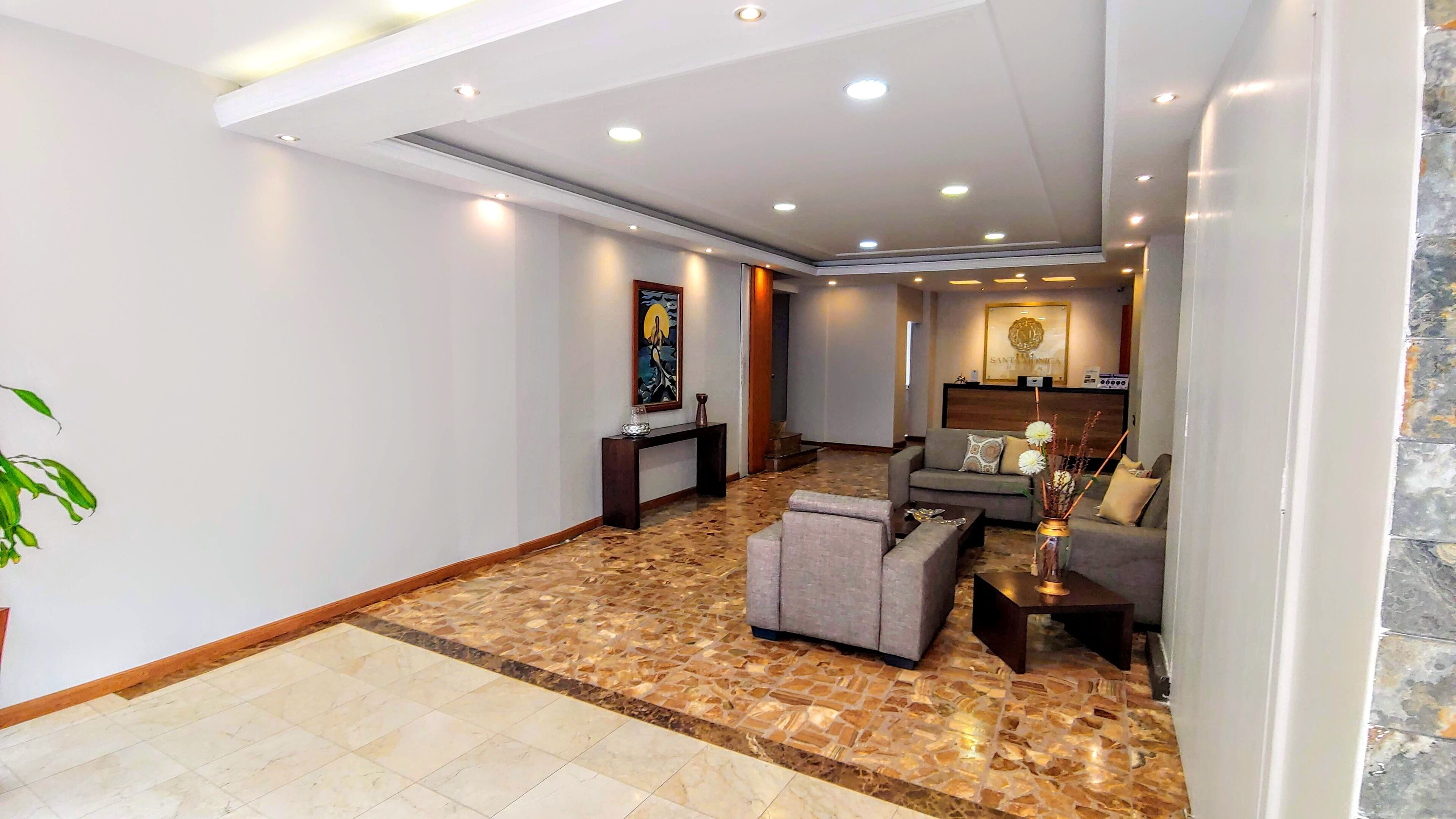 A spacious living area with a marble floor, a sofa, a coffee table, and a console table with decorative items.