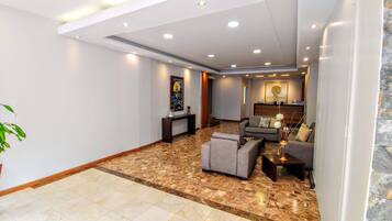 A spacious living area with a marble floor, a sofa, a coffee table, and a console table with decorative items.