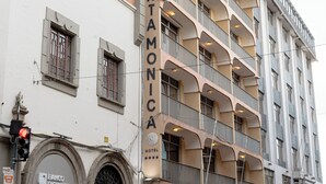 Un hotel de varios pisos con un llamativo letrero 'SANTAMONICA', con balcones y fachada de ladrillo.