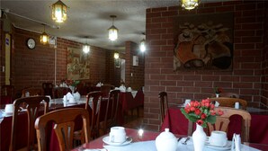 Un restaurant aux murs de briques, aux chaises en bois et aux tables dressées avec de la vaisselle blanche.