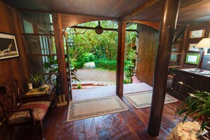 Een houten interieur met uitzicht op een tuin door een open bogenpoort.