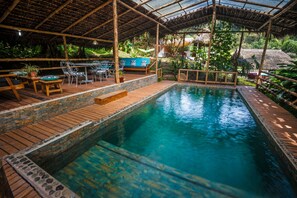 A pool area with wooden deck, seating, and a covered section. - Séptimo Paraíso (Mindo)