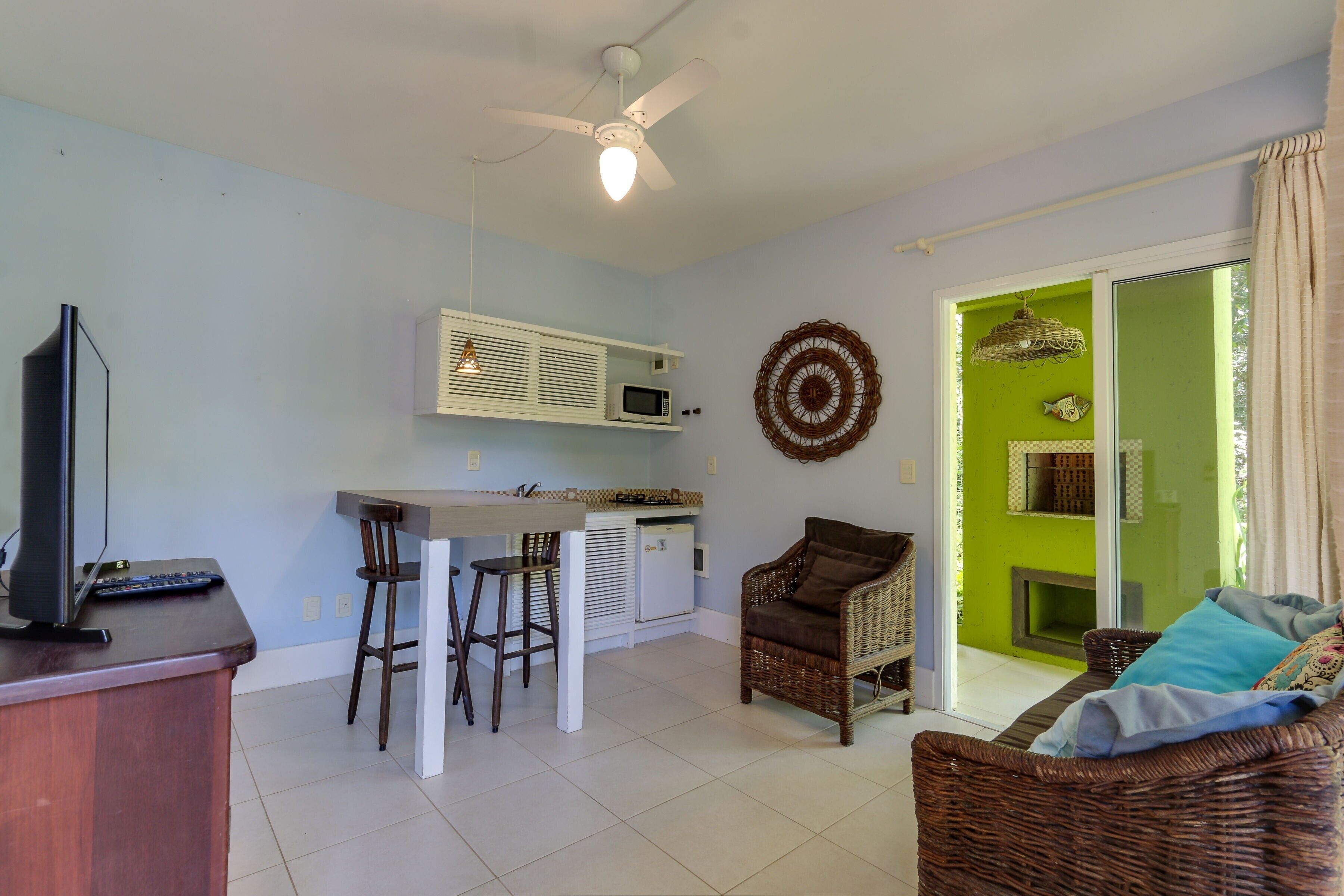 A compact living space with a kitchenette, a dining area, and a seating area with a sofa and chairs.
