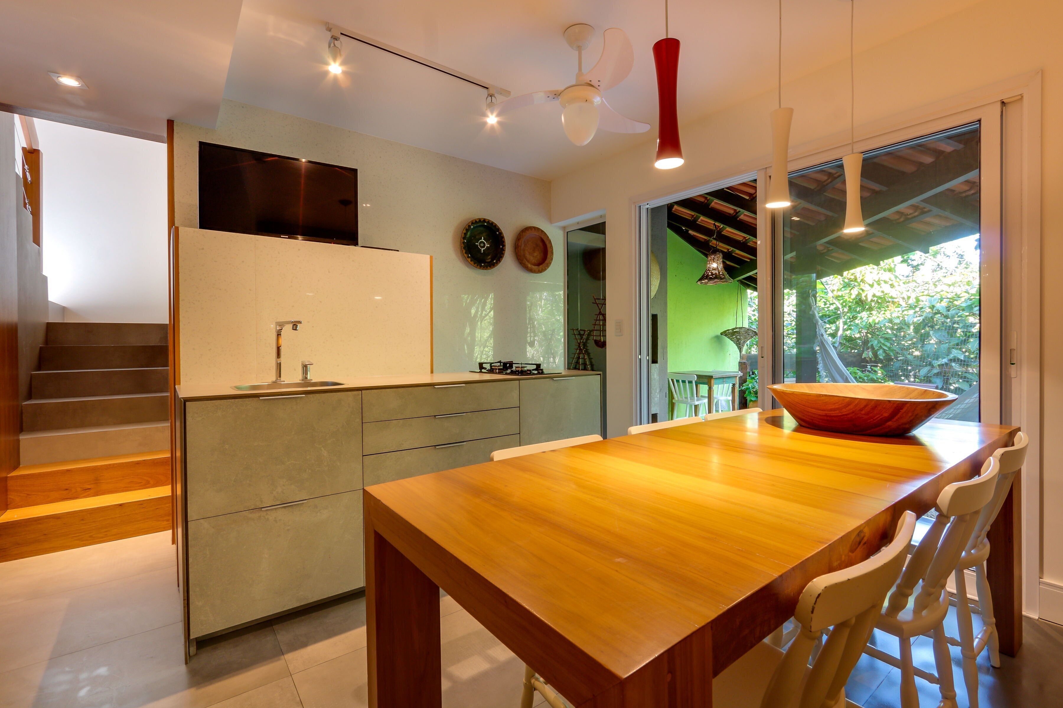 A modern kitchen with a wooden dining table, built-in appliances, and a view of the outdoors.