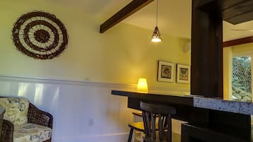 Un comedor acogedor con una silla de mimbre, una mesa de madera y una lámpara colgante.