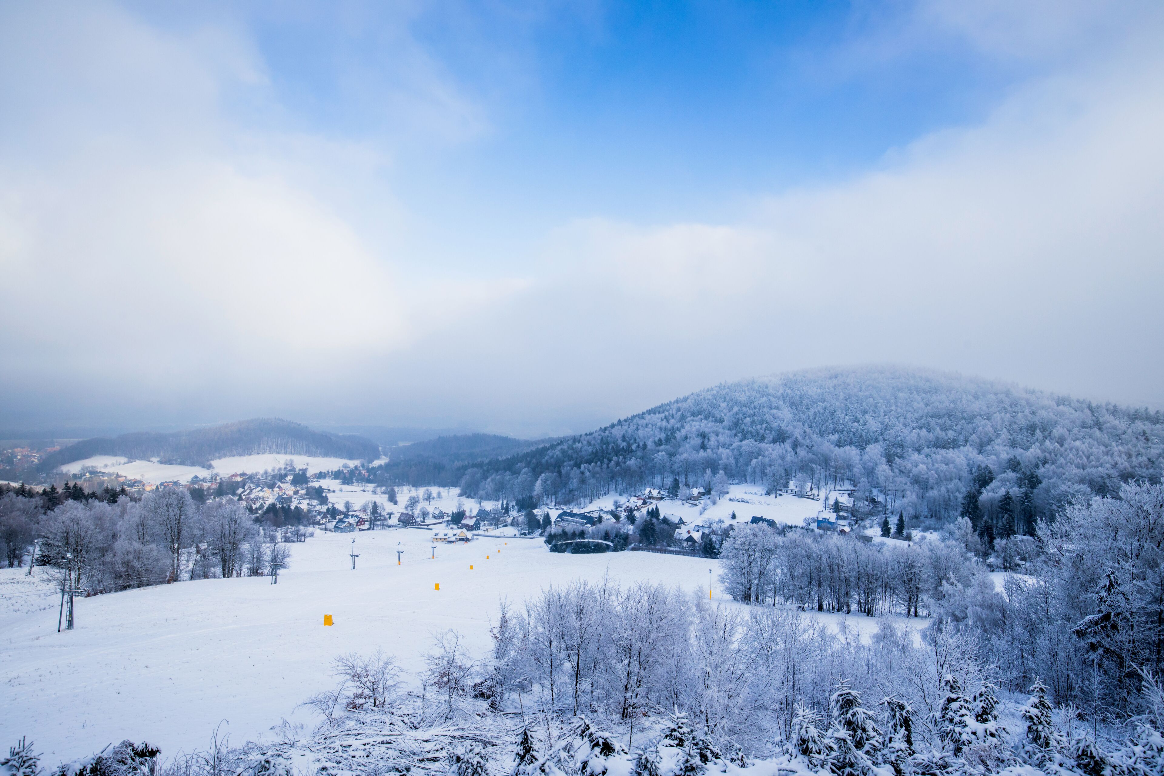 A snow-covered landscape with a ski resort, including ski lifts and a town in the valley.