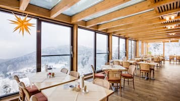 Un restaurant amb grans finestres que ofereix vistes a muntanyes cobertes de neu.