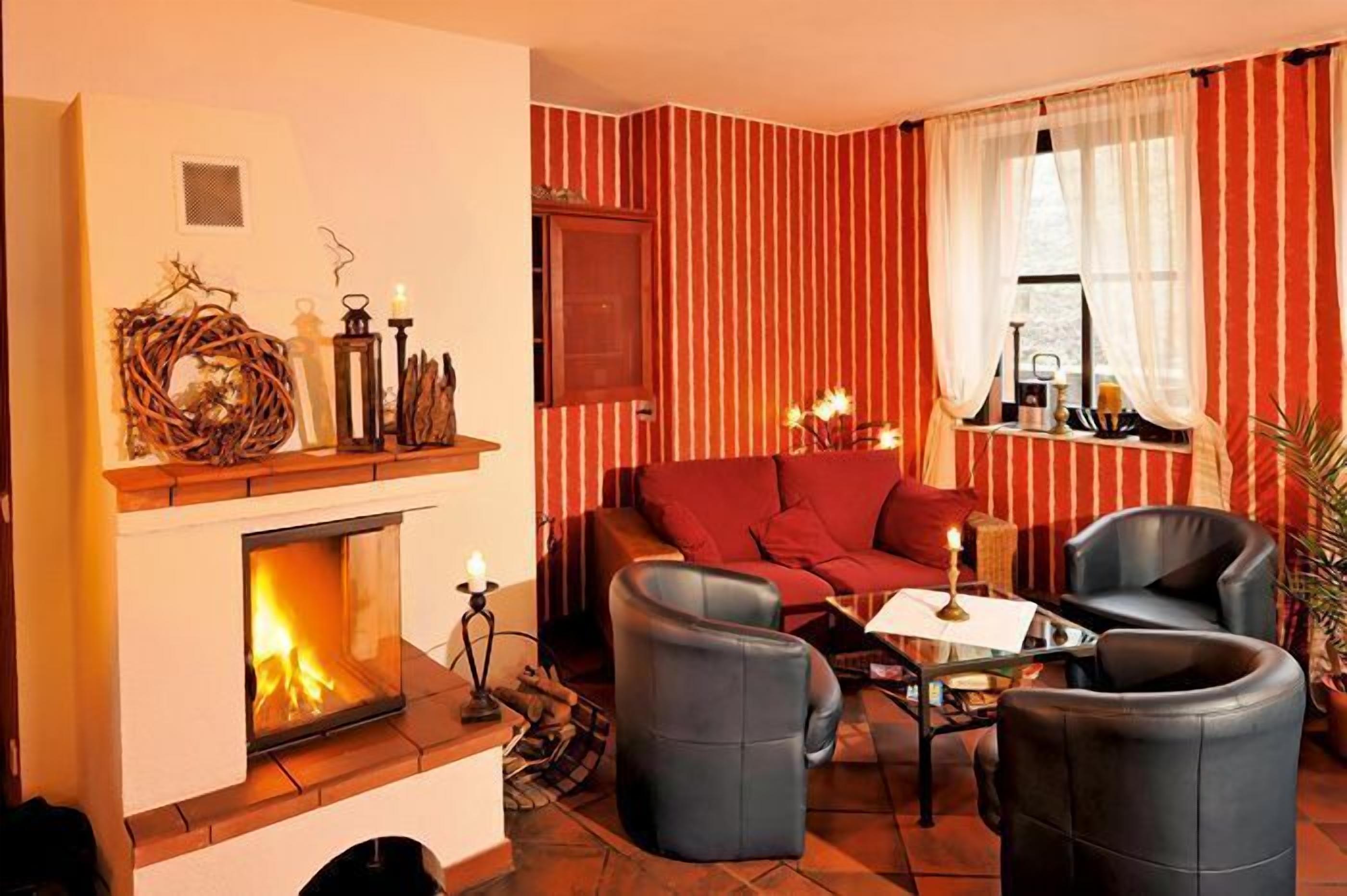 Una sala de estar acogedora con chimenea, papel tapiz a rayas y sillones de cuero.