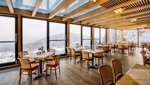 Un amplio comedor con grandes ventanales que ofrecen vistas a montañas nevadas.
