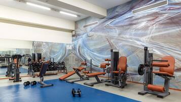A gym with exercise equipment, a blue floor, and a marble-patterned wall.