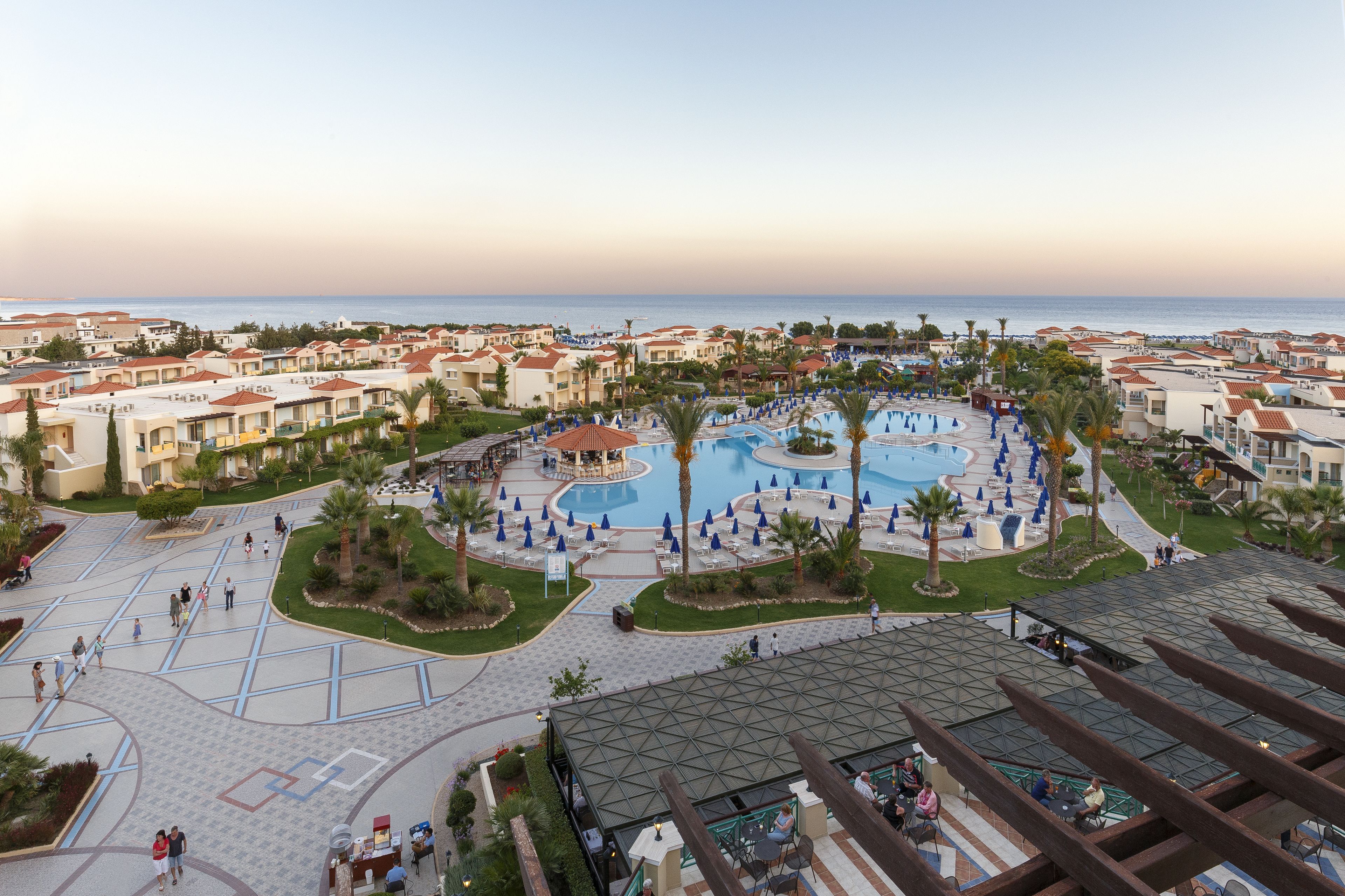 A resort with multiple swimming pools, palm trees, and a view of the sea.