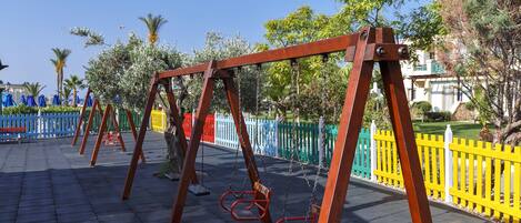 A playground with swings and a paved area.