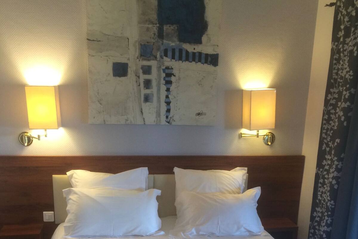 Ein Hotelzimmer mit einem großen Bett, zwei Nachttischlampen und einem Kunstwerk an der Wand.
