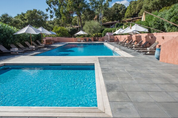 A rectangular pool with two sections, surrounded by lounge chairs and umbrellas.