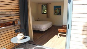 A bedroom with a bed, a chair, a table, and a window. - Les Hauts de Porto Vecchio (Porto-Vecchio)