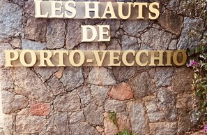 A stone wall with the text "LES HAITS DE PORTO-VECHIO" in wooden letters.