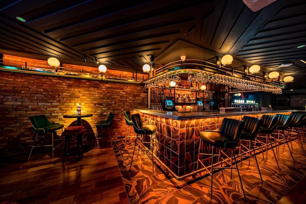 Un área de bar con pared de ladrillo, piso de madera y taburetes.