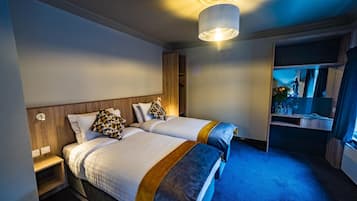 Habitación de hotel con dos camas, una mesita de noche, armario empotrado y un espejo.