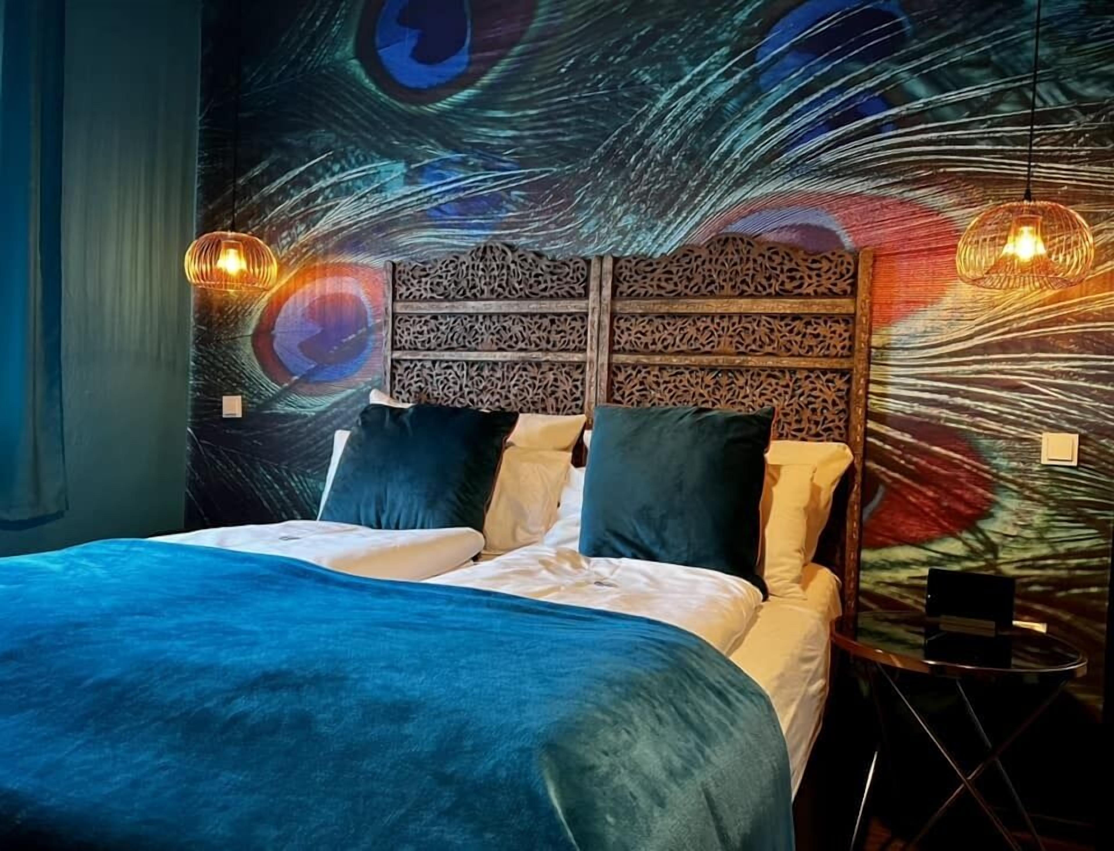Un dormitorio con cama, dos almohadas, cabecero con panel decorativo y dos lámparas de pared.