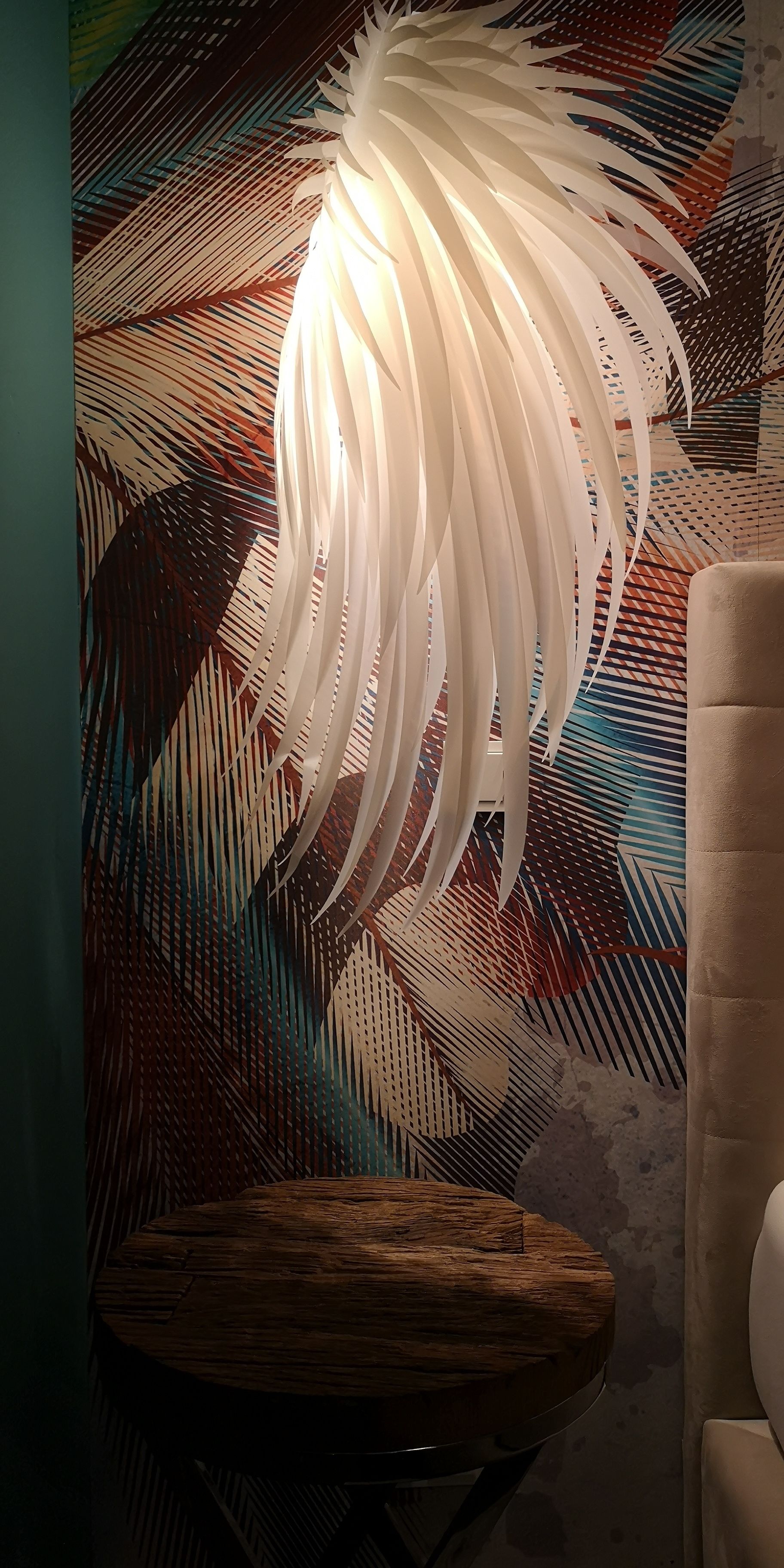 Una habitación con pared estampada, un taburete de madera y una silla blanca.