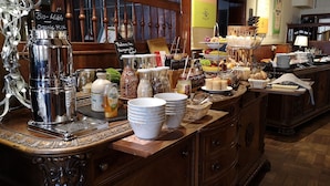 Disposição de buffet com diversos alimentos e uma máquina de café.