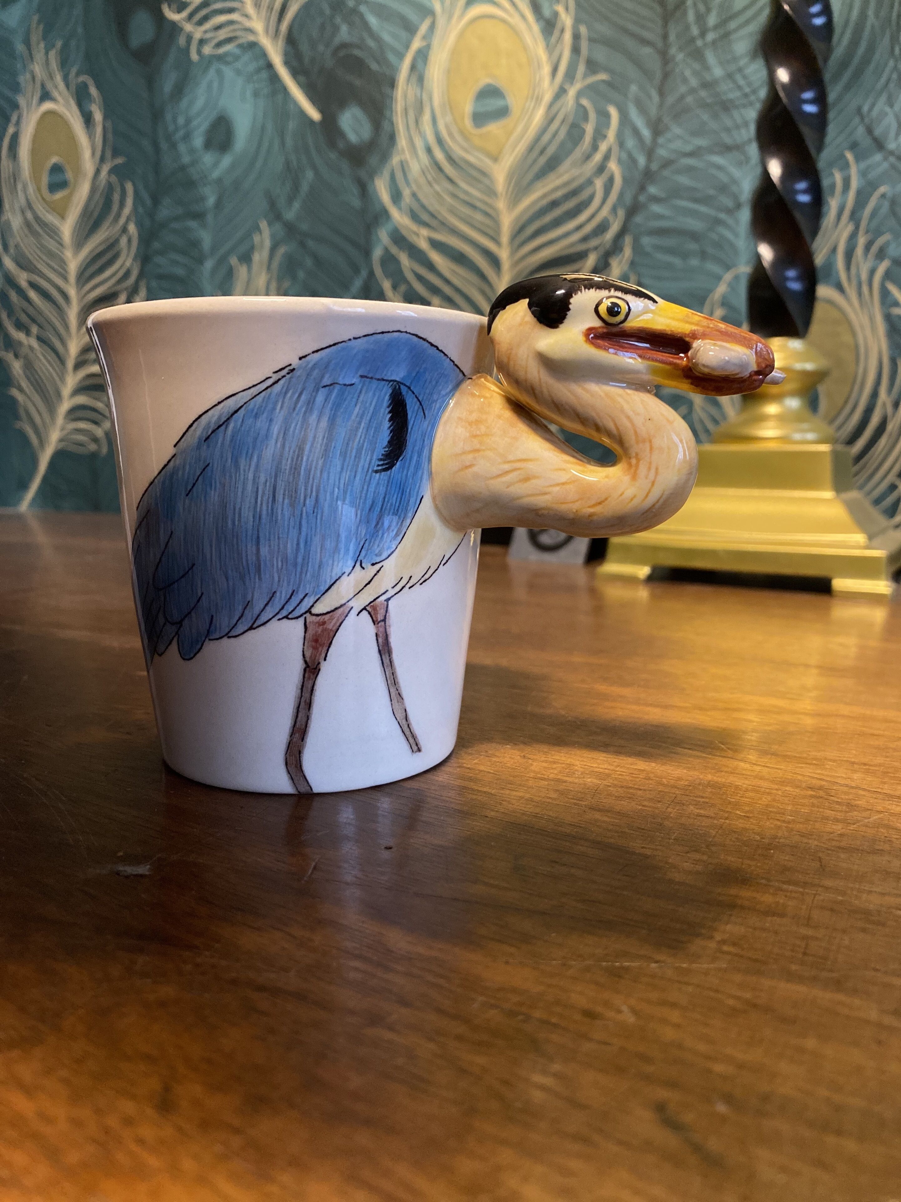 Una taza de cerámica con un diseño de pájaro y una figurita de pájaro de madera adherida.