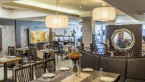 Een restaurant met houten tafels en stoelen, lantaarns van papier en een grote spiegel.