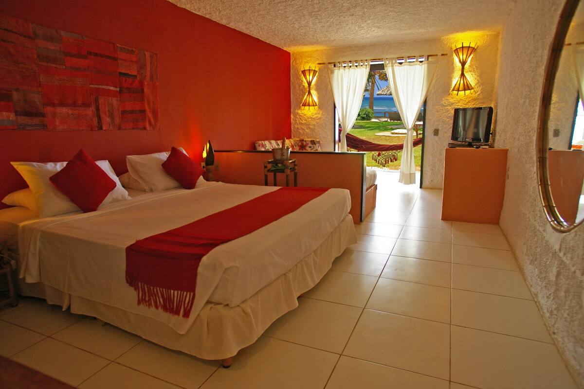 Una habitación de hotel con una cama grande, televisión y vistas al exterior.