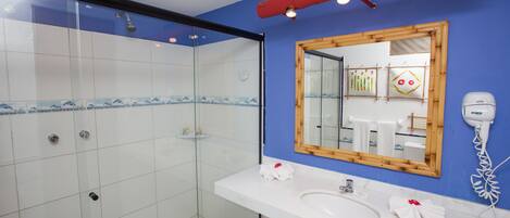 A modern bathroom with a glass shower enclosure, a white sink, and a large mirror with a wooden frame.