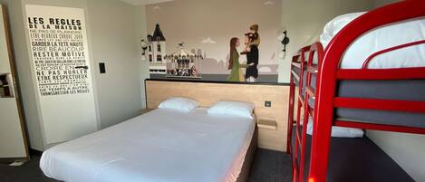 Una habitación de hotel con una cama, una litera, una pared con un mural y un cartel con texto en francés.