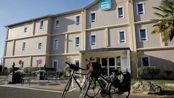 Ein mehrstöckiges Hotel mit einem Schild, auf dem 'Kyriad Direct' steht, und einem Fahrrad davor.
