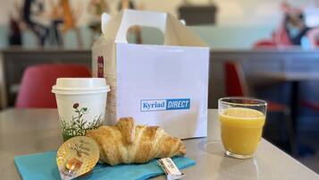 Pöydällä on croissant, kahvikuppi, mehulasi ja maitopullo.