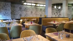 Een restaurant met zowel zitjes als losse tafels, elk voorzien van bestek en glazen.