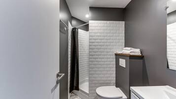 A modern bathroom with a shower, toilet, and sink.