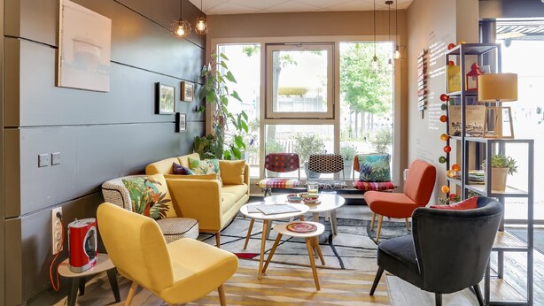 Een moderne woonkamer met een bank, stoelen, een salontafel en een boekenkast.