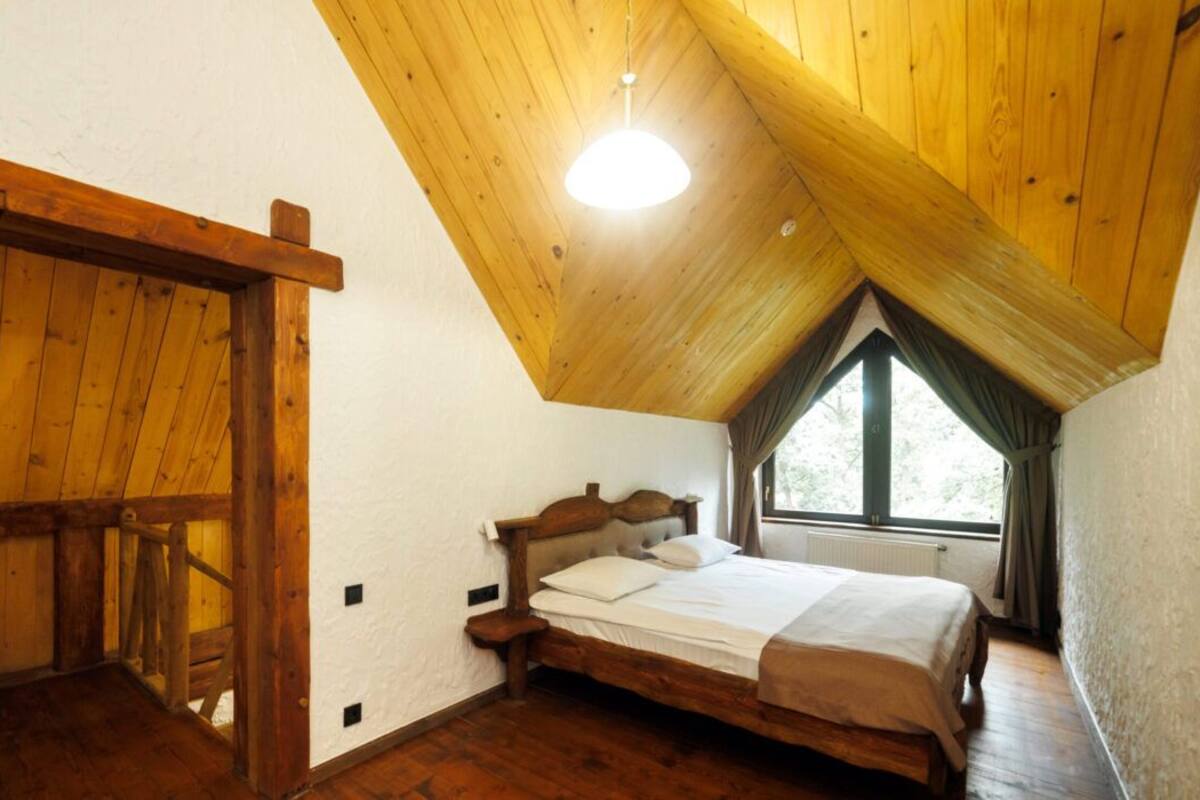 A bedroom with a wooden ceiling, a bed, and a window.