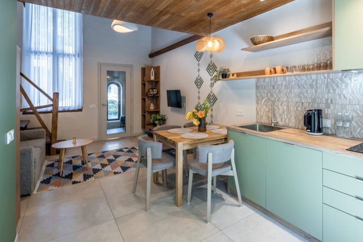 A modern kitchen with a dining area, featuring a wooden ceiling, a patterned backsplash, and a built-in stove.