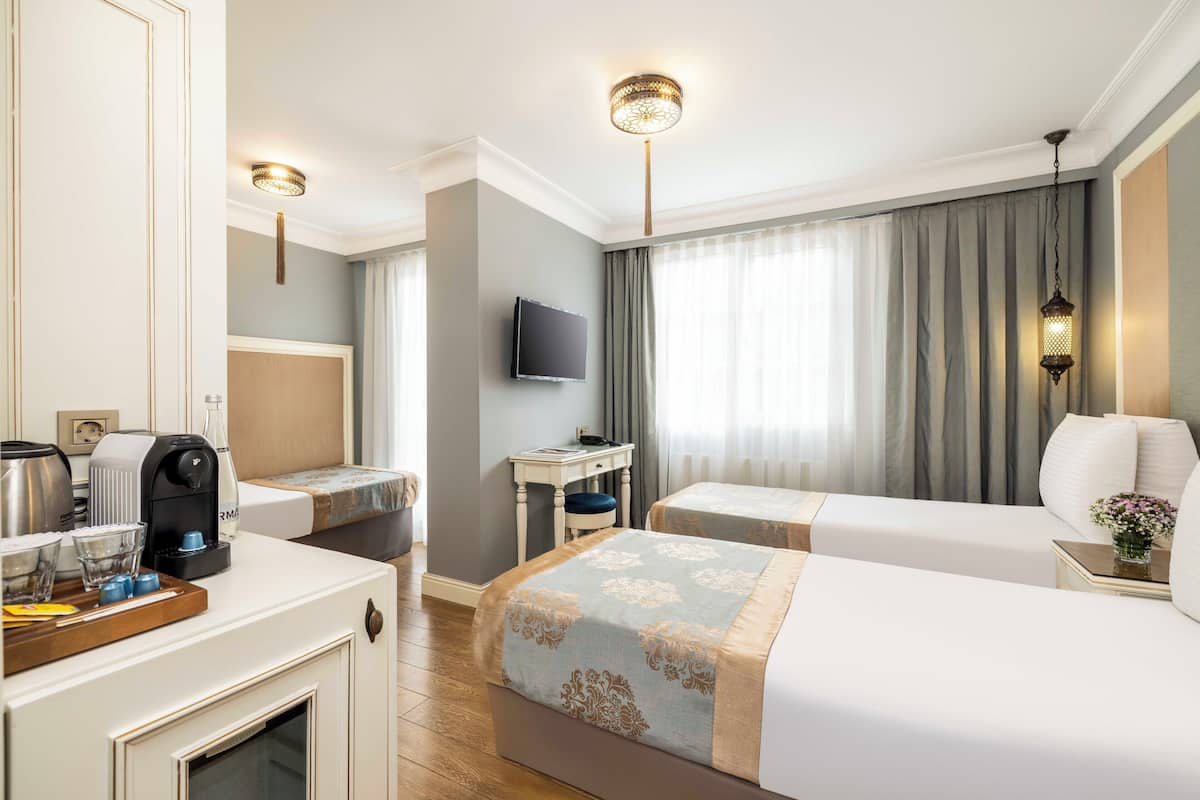 A hotel room with two beds, a desk, a television, and a coffee maker.