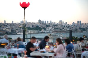 A restaurant with outdoor seating overlooking a cityscape and a body of water. - Raymond Hotel Old City (Istanbul)