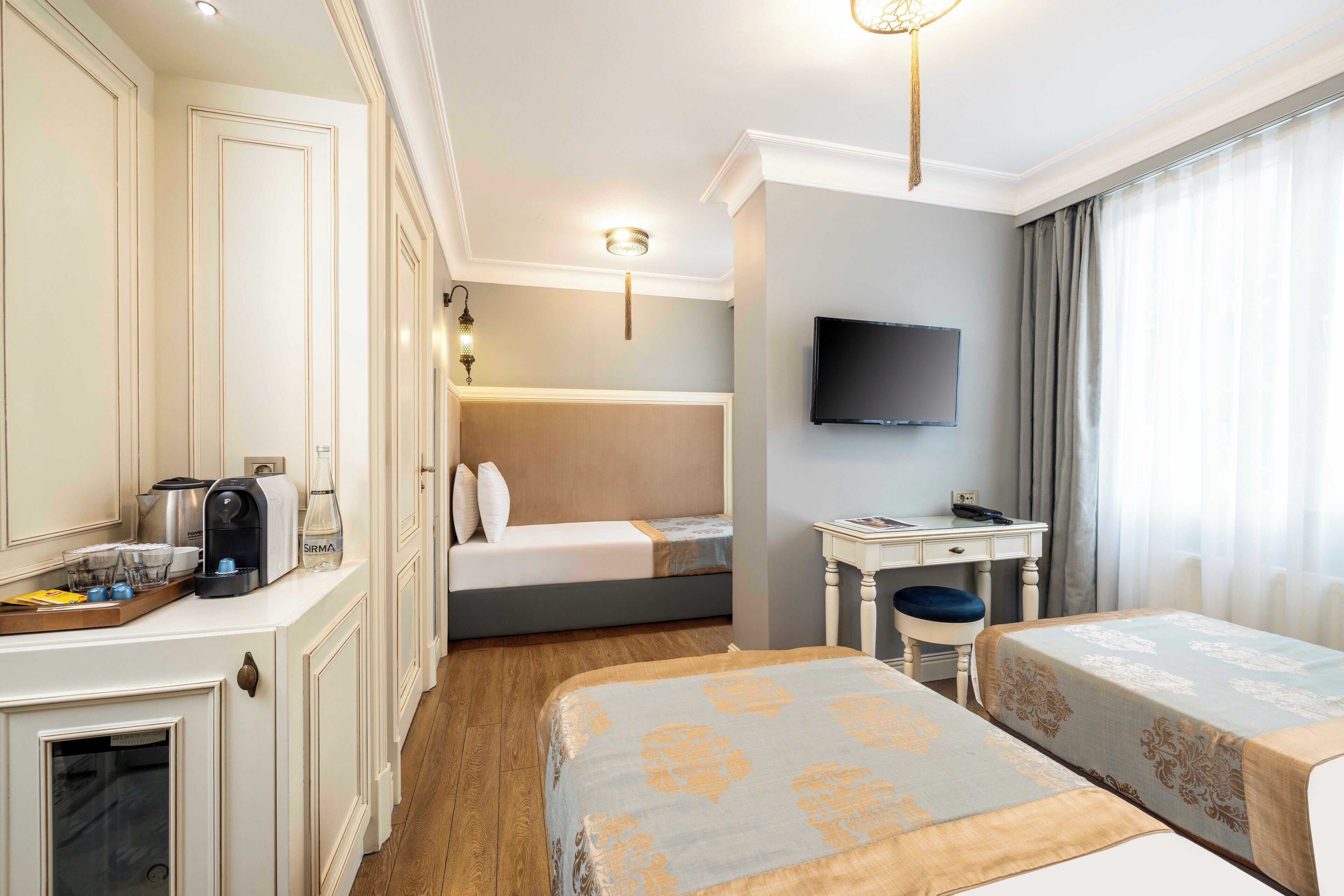 Een hotelkamer met een bed, een bureau met stoel, een televisie en een minibar.