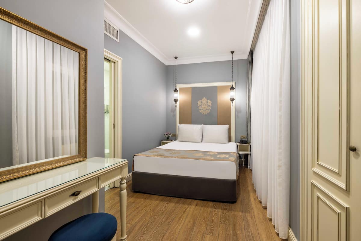 A bedroom with a large bed, a dresser, a mirror, and a nightstand.